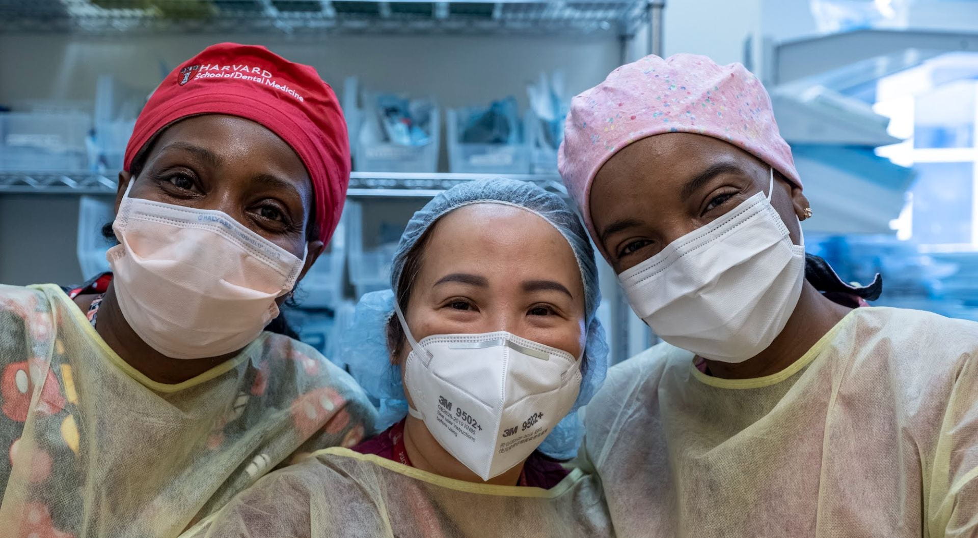 Three women wearing surgical masks looking at the camera